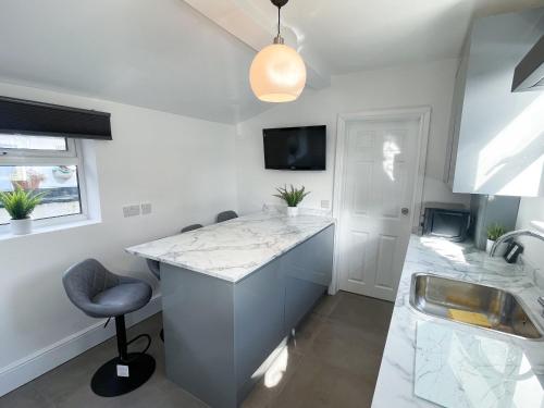 a kitchen with a counter and a sink and a stool at Tettenhall Village Townhouse in Wolverhampton