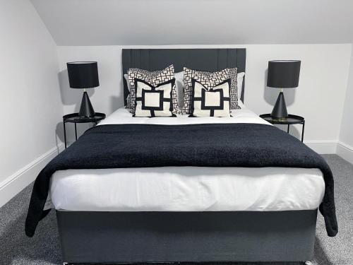 a bedroom with a large bed with black and white pillows at Tettenhall Village Townhouse in Wolverhampton
