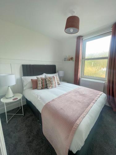 a bedroom with a large bed and a window at Tettenhall Village Townhouse in Wolverhampton