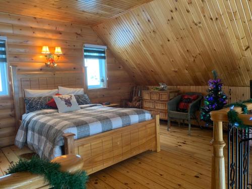 a bedroom in a log cabin with a bed and a christmas tree at Chalets Garou in St-Ferdinand