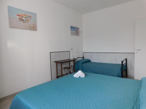 Un dormitorio con una cama azul y una mesa en Lovely PitStop Fiumicino en Fiumicino
