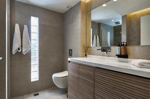 uma casa de banho com um lavatório, um WC e um espelho. em Pachnes Luxury Apartments - Heated Pool, Sea View em Kounoupidhianá