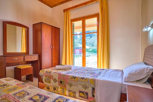 1 dormitorio con 2 camas y ventana en Theodora Apartments Agios Stefanos Corfu en Agios Stefanos