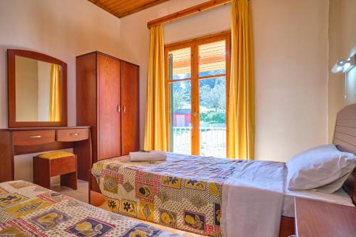 1 dormitorio con 2 camas y ventana en Theodora Apartments Agios Stefanos Corfu, en Agios Stefanos