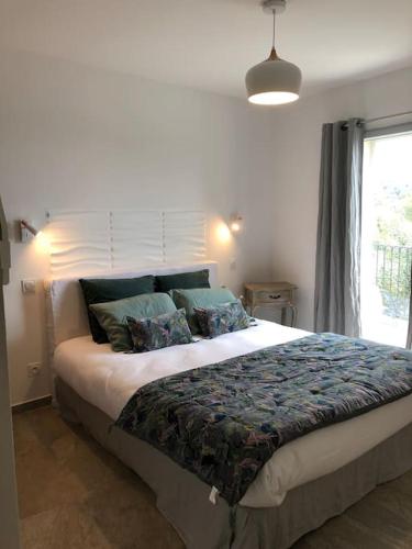 une chambre avec un grand lit avec des oreillers et une fenêtre dans l'établissement Très belle Villa familiale Cap Corse, à Brando