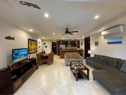 a living room with a couch and a flat screen tv at Monte Carlo Luxury Condominiums in Jacó