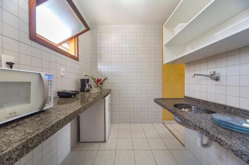 y baño con lavabo y microondas. en America Praia Flat - Portal Hotéis, en Porto Seguro