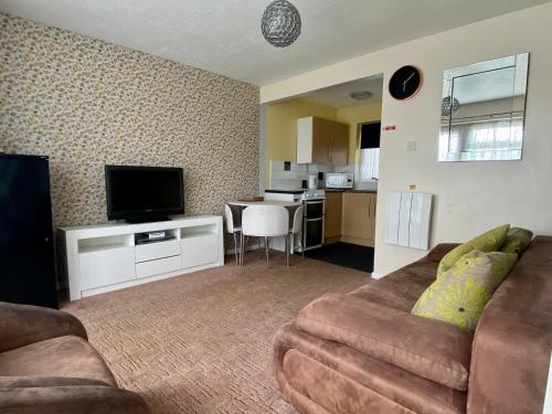 a living room with a couch and a flat screen tv at Cosy and Comfortable Holiday Chalet 10 minutes walk to the beach, Norfolk in Great Yarmouth