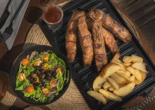 a tray of food with sausage and salad and a plate of fries at El Rio Hotel in Doradal