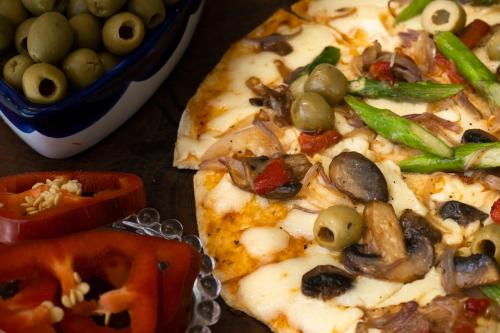 a pizza with mushrooms and green peppers and a bowl of olives at El Rio Hotel in Doradal
