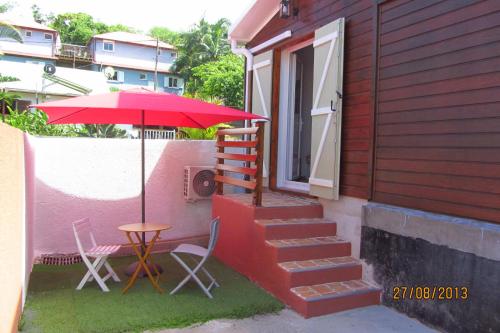 une terrasse avec une table, des chaises et un parasol dans l'établissement Chez Frida, à Entre-Deux