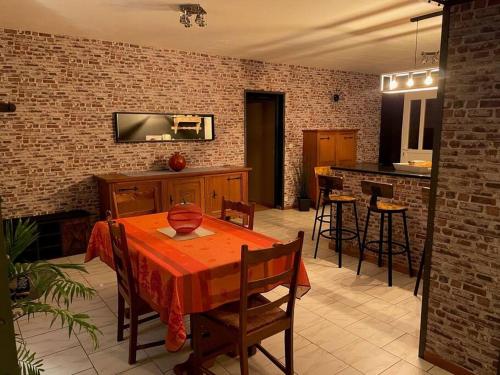 een woonkamer met een tafel en een bakstenen muur bij La Bergerie in Thilay
