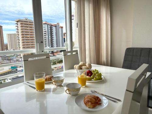 a table with plates of food and glasses of orange juice at Domo 5E Holiday apt with pool in Benidorm