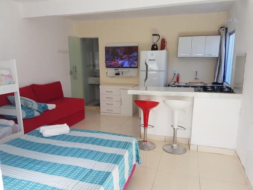 uma sala de estar com um sofá vermelho e uma cozinha em Residencial dos Ipês em Itacaré
