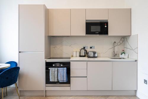 a kitchen with white cabinets and a microwave at Modern Apartments Near Harrods and the Science Museum in London