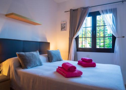 twee roze handdoeken op een bed met een raam bij Dias Felices in Playa Blanca