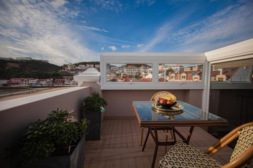 a balcony with a table and a view of a city at Storytellers Palace in São Martinho do Porto