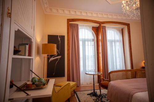 a bedroom with a bed and a desk and windows at Storytellers Palace in São Martinho do Porto