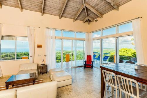 sala de estar con mesa, sillas y ventanas en Vieques Villa Gallega - Oceanview w/Infinity Pool en Vieques