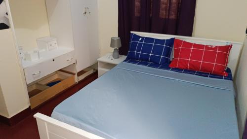 a bedroom with a bed with red and blue pillows at Casa de Férias in Tarrafal