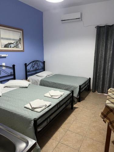 two beds in a room with blue walls at Stella Nomikou Apartments in Firostefani
