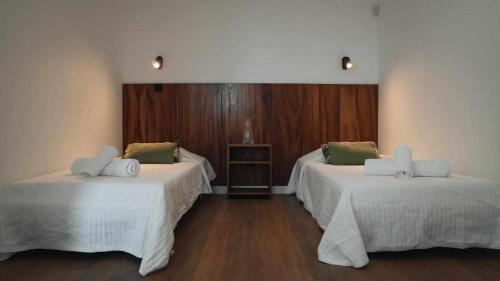 ノルデスチにあるCasas do Vale A Casa Casa familiarの白いシーツと木製の床が備わる2人部屋です。