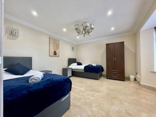 a large bedroom with two beds and a chandelier at Luxurious Kitchen, 4BR Home with Free Parking near Airport for Contractor Holiday for 8 People in Luton