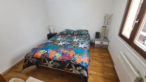 sypialnia z łóżkiem z kolorową kołdrą w obiekcie Selestat entre Colmar et Strasbourg w mieście Sélestat