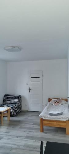 a room with a bed and a bench and a door at UniBal - pokoje gościnne in Unieście