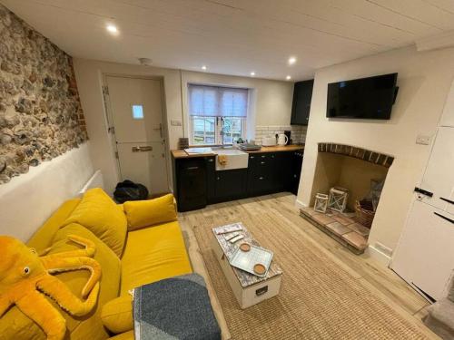 a living room with a yellow couch and a kitchen at Haven Cottage, Cromer in Cromer