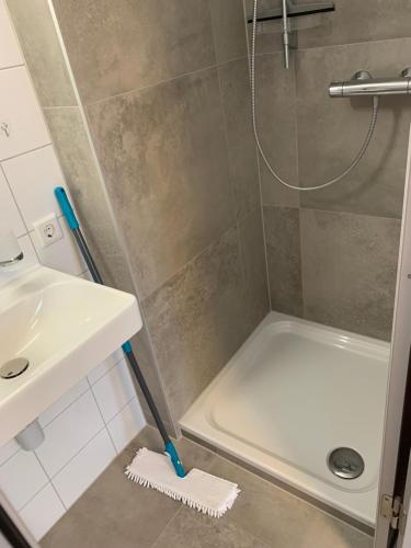 a bathroom with a shower with a white mop next to a sink at Kleine drei Länderzentrale in Hohenems