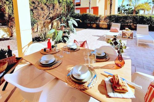 een houten tafel met borden eten op een patio bij PtBja a estrenar GranTerraza Piscinas Altaona Golf in Murcia