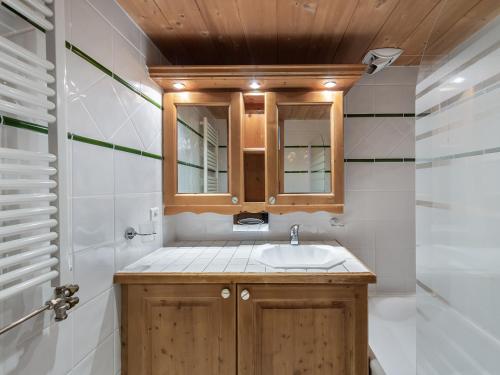 une salle de bain avec un lavabo et un miroir dans l'établissement Appartement cosy ski aux pieds avec piscine et spa - FR-1-566-46, à Les Allues