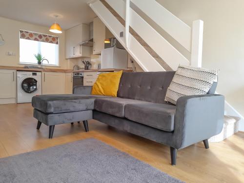 a living room with a couch and a kitchen at Modern Cotswold Home in Witney