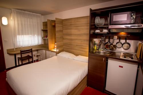 a small bedroom with a white bed and a kitchen at So'Lodge Niort A83 in La Creche