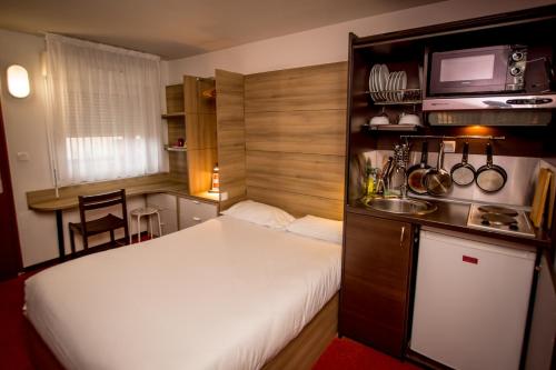 ラ・クレッシュにあるSo'Lodge Niort A83の小さなベッドルーム(白いベッド1台付)、キッチンが備わります。