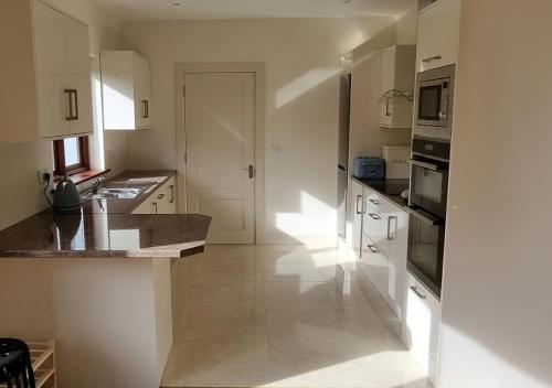 a kitchen with white cabinets and a counter top at 4 bedroom Holiday Home In Union Hall, West Cork in Union Hall