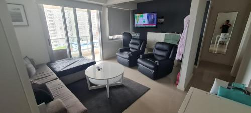 a living room with a couch and a table and chairs at Jose Luis Arenas del Mar Torre 1 in Punta del Este