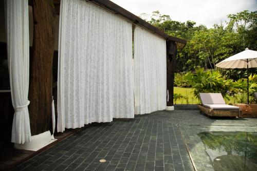 a patio with white curtains and a chair and an umbrella at El Rio Hotel in Doradal