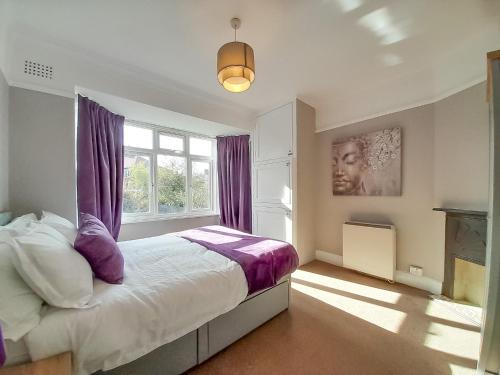 a bedroom with a bed with purple curtains and a window at Rose Hill Apartment in Oxford