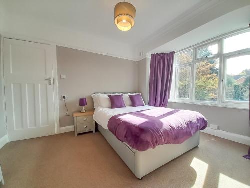 a bedroom with a bed with purple sheets and a window at Rose Hill Apartment in Oxford