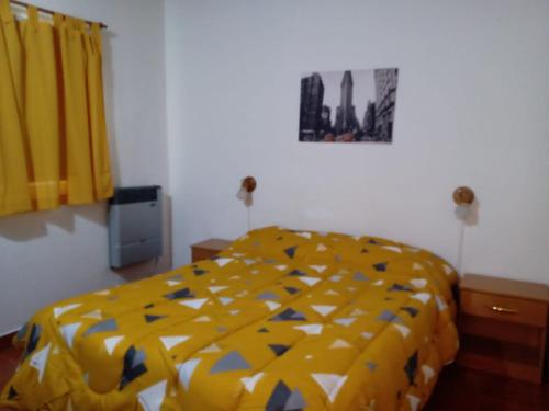1 dormitorio con 1 cama con edredón amarillo en Luz de luna en Esquel