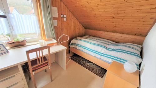 een kleine kamer met een bed, een bureau en een raam bij Ferienwohnung am Schwarzwaldrand in Nagold