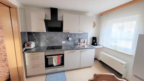 uma cozinha com armários brancos e um forno com placa de fogão em Ferienwohnung am Schwarzwaldrand em Nagold