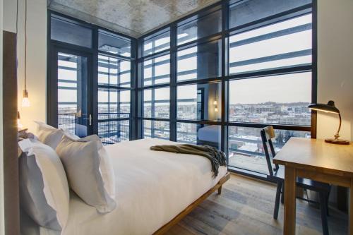a bedroom with a bed and a desk and windows at Boro Hotel in Queens