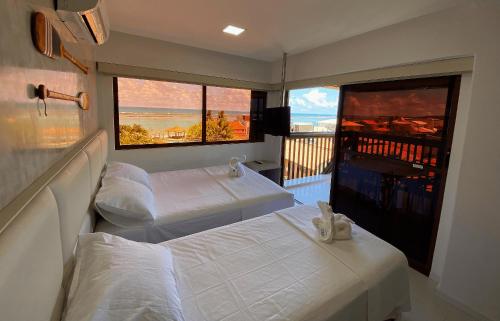 a hotel room with two beds and a balcony at Barra Bali, com incrível vista para o mar! - Destino BSM 209 in Barra de São Miguel