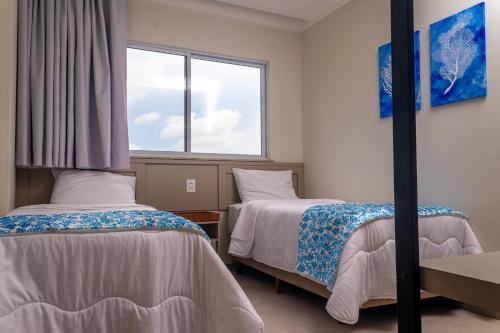 two beds in a room with a window at Aqualand Park & Resort Oficial in Salinópolis