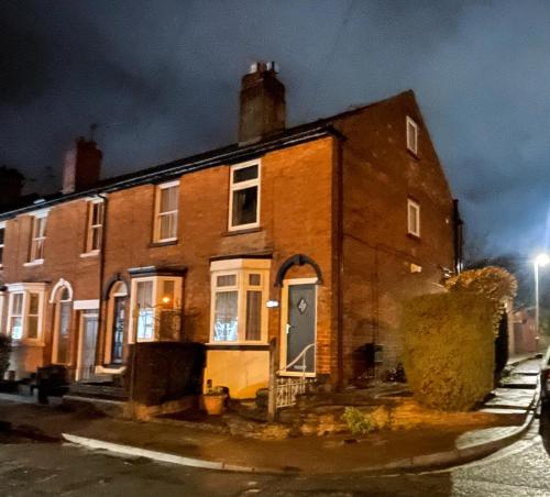 a brick house on a street at night at Tettenhall Village Townhouse in Wolverhampton