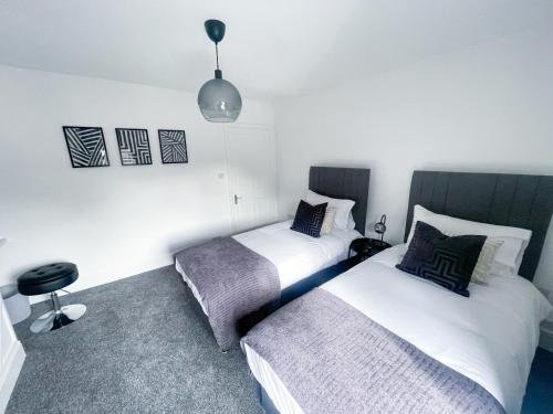 a bedroom with two beds and a chair in it at Tettenhall Village Townhouse in Wolverhampton