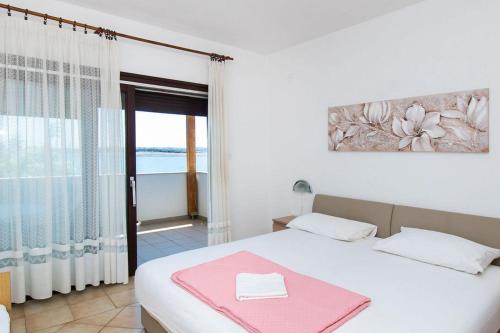 a bedroom with a bed with a pink towel on it at Apartments Crljenko in Povljana